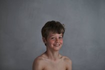 Porträt eines lächelnden Jungen auf grauem Hintergrund — Stockfoto