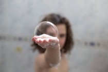 Girl in bath holding a soap sud in her hand — Stock Photo