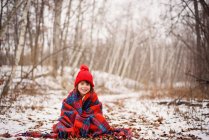 Дівчина сидить у снігу, загорнута в ковдру — стокове фото