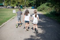 Drei Kinder laufen Fußweg im Park entlang — Stockfoto
