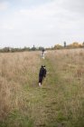 Visão traseira da menina correndo com seu cão — Fotografia de Stock