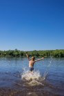 Мальчик, брызгающийся в реке на природе — стоковое фото