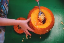 Girl removing seeds from a pumpkin — Stock Photo