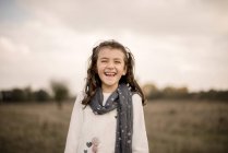 Retrato de uma menina de pé em um campo rindo — Fotografia de Stock