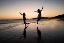 Silhouette de deux femmes dansant sur la plage de los Lances au coucher du soleil, Tarifa, Cadix, Andalousie, Espagne — Photo de stock