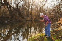 Femme âgée regardant dans la rivière — Photo de stock