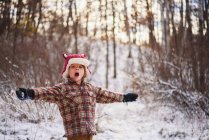 Портрет хлопчика, що стоїть у снігу з простягнутими руками — стокове фото