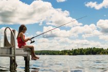 Menina sentada na doca pesca — Fotografia de Stock