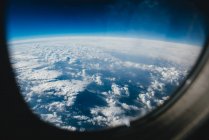 Nuages à travers une fenêtre d'avion — Photo de stock