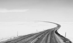 Пустая дорога через зимний пейзаж, Исландия — стоковое фото