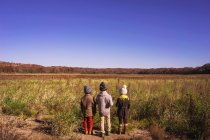 Three children standing in a meadow — Stock Photo