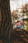 Grandmother and granddaughter sitting in forest hugging — Stock Photo