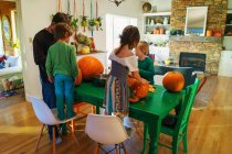 Father and three children preparing pumpkins in kitchen — Stock Photo
