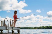 Дівчина стоїть на причалі риболовлі в сонячний день — стокове фото