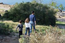Père et deux enfants se promènent dans un paysage rural — Photo de stock