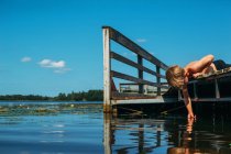 Adorable little boy on old wooden pier — Stock Photo