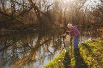 Grand-mère pointant vers la rivière avec sa petite-fille — Photo de stock