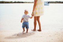 Mother and son at the beach standing at water's edge — Stock Photo