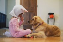 Girl in bunny costume sharing Halloween candy with Golden Retriever dog — Stock Photo
