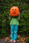 Boy holding a jack-o-lantern in front of his face — Stock Photo