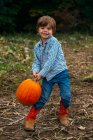 Boy carrying a heavy pumpkin — Stock Photo