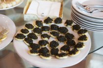 Caviar preto e canapés blini sobre placa branca — Fotografia de Stock