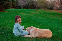 Menina brincando com seu cão golden retriever no jardim — Fotografia de Stock