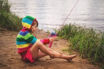 Menina sentada à beira do rio pesca — Fotografia de Stock