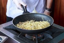 Обрізане зображення кухаря, який готує спагетті на сковороді — стокове фото