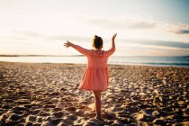 Mädchen steht tanzend am Strand, Rückansicht — Stockfoto