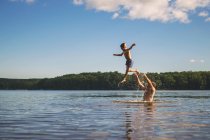 Father throwing son in the air while standing in a lake — Stock Photo