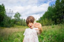 Mädchen steht auf einem Feld und hält ein Blatt — Stockfoto