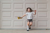 Girl standing in front of garage door holding flowers — Stock Photo