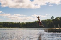 Homem saltando da doca em um lago — Fotografia de Stock
