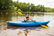 Boy paddling in kayak on nature — Stock Photo
