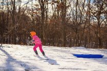 Menina puxando seu trenó através da neve — Fotografia de Stock