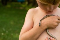 Boy holding a snake on nature — Stock Photo
