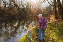 Бабуся тримає руки з онукою біля річки — стокове фото