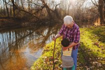 Girl hugging her grandmother in forest by a river — Stock Photo