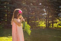 Fille debout dans le jardin manger une carotte fraîchement cueillie — Photo de stock