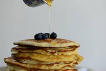 Syrup being poured on a stack of pancakes with blueberries — Stock Photo