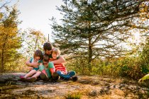 Vater sitzt im Wald und umarmt drei Kinder — Stockfoto