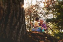 Abuela y nieta sentadas en el bosque hablando - foto de stock
