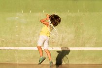 Хлопчик грає в теніс і кидає тінь — стокове фото