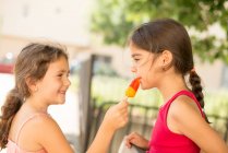 Two girls sharing an ice-lolly — Stock Photo