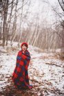 Porträt eines in eine Decke gehüllten Mädchens, das lachend im Schnee steht — Stockfoto
