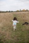 Menina correndo através do campo com seu cão — Fotografia de Stock