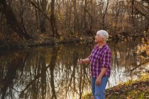 Seniorin steht an einem Fluss — Stockfoto