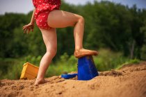Ragazza che gioca nella sabbia sulla spiaggia — Foto stock