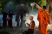 Retrato de un monje vertiendo agua sobre la cabeza de otro monje, Tailandia - foto de stock